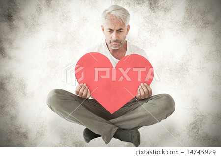 Composite image of upset man sitting holding heart shape Composite image of upset man sitting holding heart shape 14745929