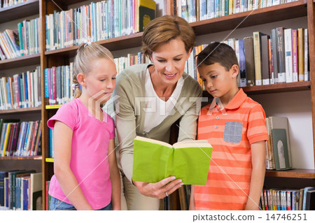 Teacher reading book with pupils at library 14746251