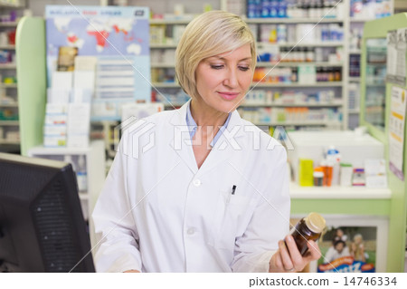 Pharmacist looking at medicine bottle 14746334