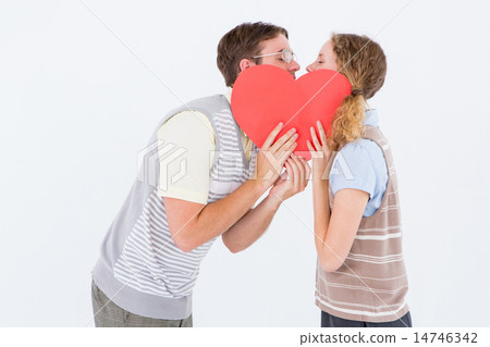 Geeky hipster couple kissing behind heart card 14746342
