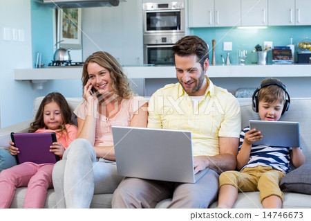 Happy family on the couch together using devices 14746673