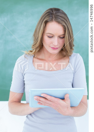 Smiling teacher using tablet pc in front of blackboard Smiling teacher using tablet pc in front of blackboard 14746996
