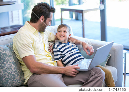 Father and son using laptop on the couch Father and son using laptop on the couch 14748260