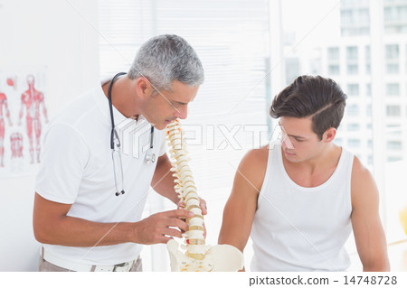 Doctor showing anatomical spine to his patient Doctor showing anatomical spine to his patient 14748728