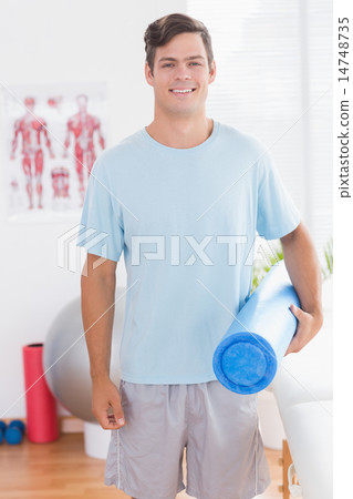 Happy young man holding exercise mat 14748735