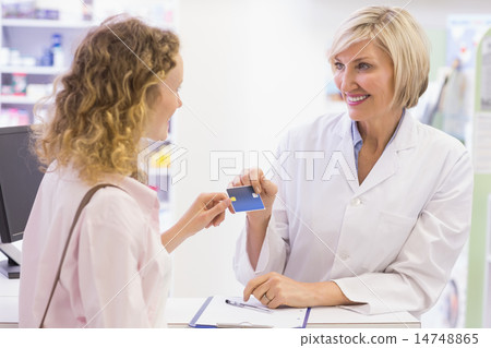 Pharmacist giving credit card to costumer 14748865