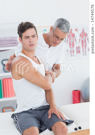 Doctor stretching a young man arm Doctor stretching a young man arm 14749576