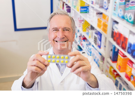 Senior pharmacist holding up blister packs Senior pharmacist holding up blister packs 14750398