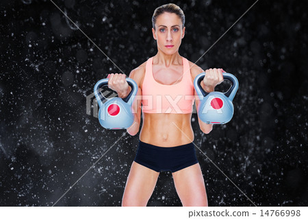 Composite image of serious female crossfitter lifting kettlebell 14766998