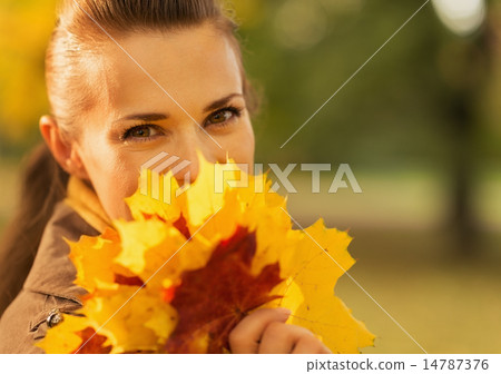 Happy woman hiding behind bunch of fallen leaves Happy woman hiding behind bunch of fallen leaves 14787376