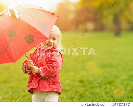 Smiling baby looking out from red umbrella Smiling baby looking out from red umbrella 14787377