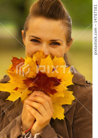 Happy woman hiding behind bunch of fallen leaves Happy woman hiding behind bunch of fallen leaves 14787381