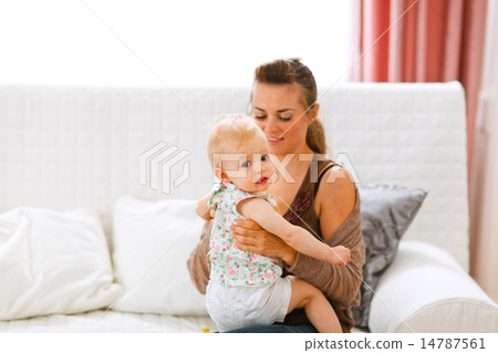Funny baby sitting on mamas knees and looking back Funny baby sitting on mamas knees and looking back 14787561