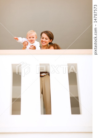 Portrait of mother with happy baby looking down from railing Portrait of mother with happy baby looking down from railing 14787573