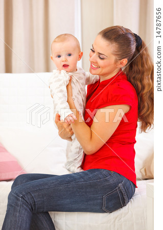 Baby playing with mother on divan 14787656