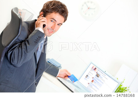 Smiling businessman in office making purchase by phone and credit card. Smiling businessman in office making purchase by phone and credit card. 14788168