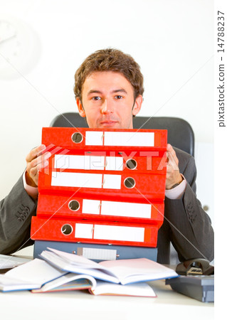 Sitting at office desk confused businessman looking out from pil 14788237