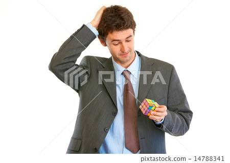 Confused businessman holding Rubik's cube in hand 14788341