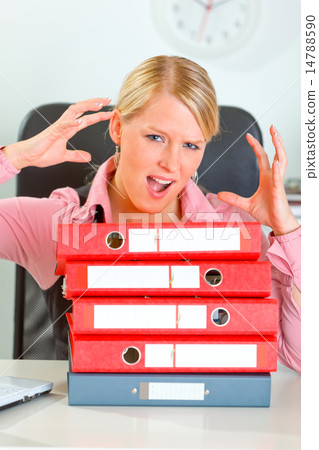 Stressed modern female manager with pile of folders at office de 14788590