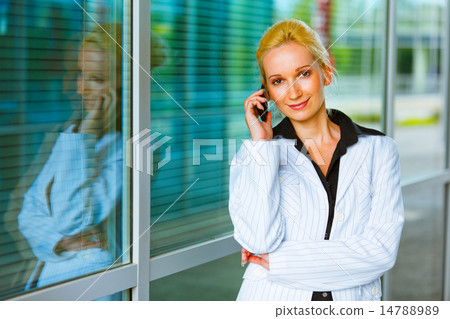 Smiling business woman talking on mobile at office building Smiling business woman talking on mobile at office building 14788989