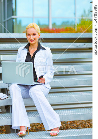 Happy business woman sitting on stairs at office building and wo Happy business woman sitting on stairs at office building and wo 14788998