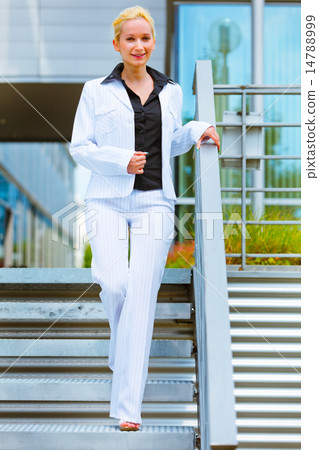 Smiling business woman walking down stairs Smiling business woman walking down stairs 14788999