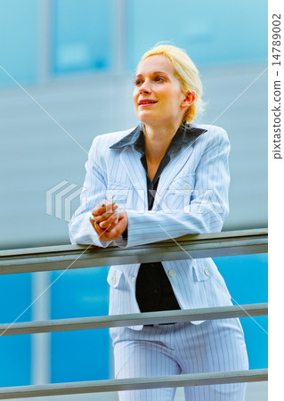 Pensive business woman leaning on railing at office building loo 14789002