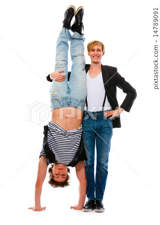 Young man holding his standing upside down friend. Isolated on w Young man holding his standing upside down friend. Isolated on w 14789091
