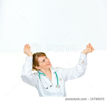 Smiling medical doctor woman looking at blank billboard. 14790035