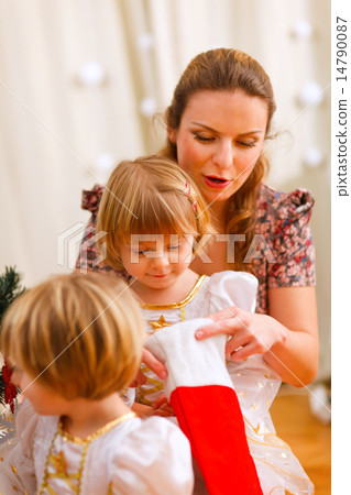 Mother looking with twins daughters inside of Christmas socks 14790087