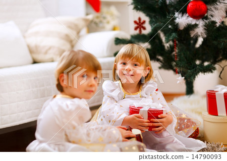 Two girls sitting with presents near Christmas tree Two girls sitting with presents near Christmas tree 14790093