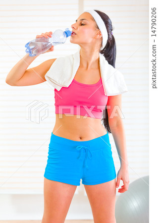 Fitness girl with towel around neck drinking water from bottle Fitness girl with towel around neck drinking water from bottle 14790206