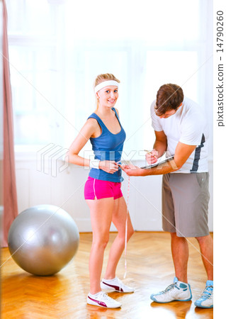 Personal trainer measuring belly of girl in sportswear 14790260