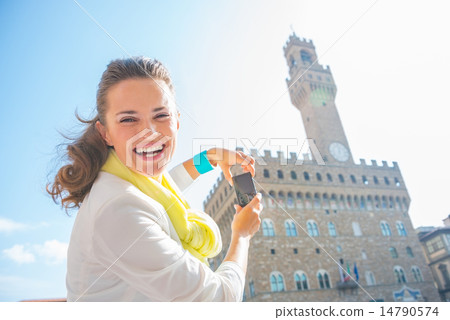 Happy young woman taking photo of palazzo vecchio in florence, i 14790574