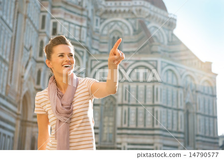 Portrait of happy young woman pointing on copy space in front of 14790577