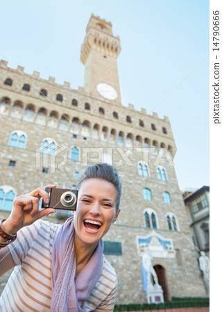 Portrait of smiling young woman with photo camera in front of pa Portrait of smiling young woman with photo camera in front of pa 14790666