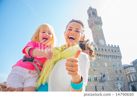 Happy mother and baby girl showing thumbs up in front of palazzo Happy mother and baby girl showing thumbs up in front of palazzo 14790680