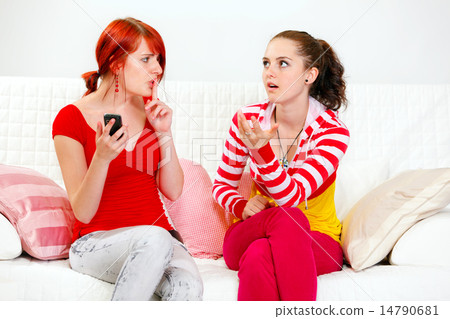 Girl with mobile showing silence gesture her indignant girlfriend. Girl with mobile showing silence gesture her indignant girlfriend. 14790681