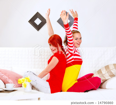 Two beautiful girlfriends sitting on sofa back to back and rejoi Two beautiful girlfriends sitting on sofa back to back and rejoi 14790860
