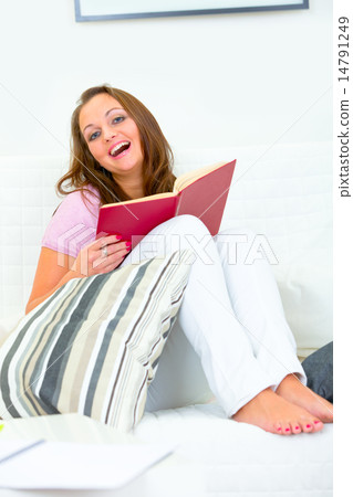 Laughing attractive woman sitting on couch with book. Laughing attractive woman sitting on couch with book. 14791249