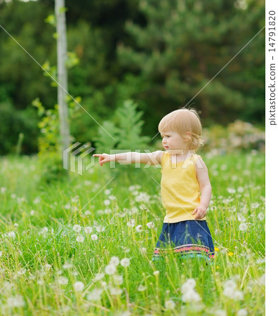 Baby girl on dandelions field pointing on copy space Baby girl on dandelions field pointing on copy space 14791820