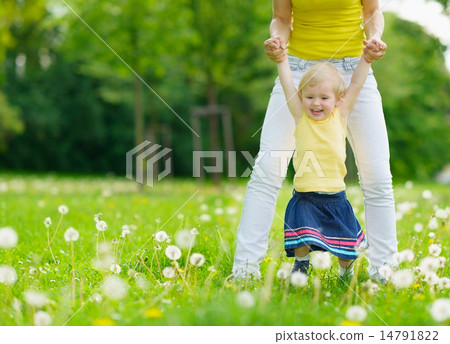 Mother playing with baby girl on dandelions field Mother playing with baby girl on dandelions field 14791822