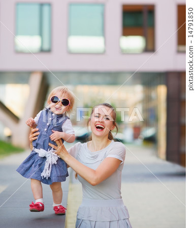Smiling mother playing with baby in city Smiling mother playing with baby in city 14791850