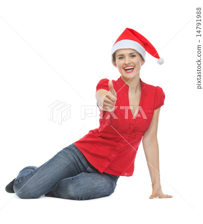 Happy woman in Christmas hat sitting on floor and showing thumbs 14791988