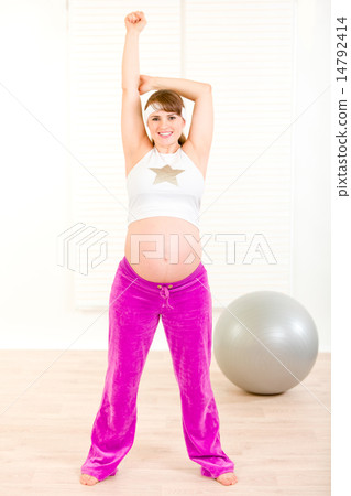 Smiling beautiful pregnant woman doing exercise at home. 14792414