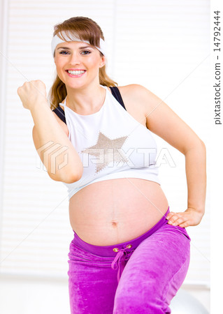 Smiling beautiful pregnant woman doing fitness exercises at home. 14792444
