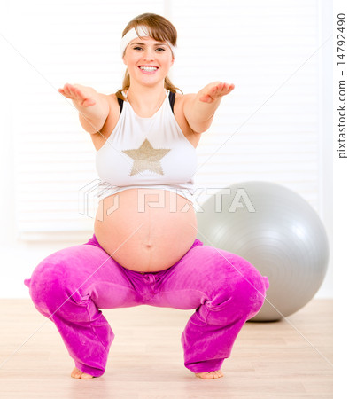 Smiling beautiful pregnant woman doing exercise at home. 14792490