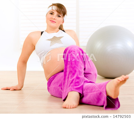 Smiling beautiful pregnant female making gymnastics at living room. 14792503