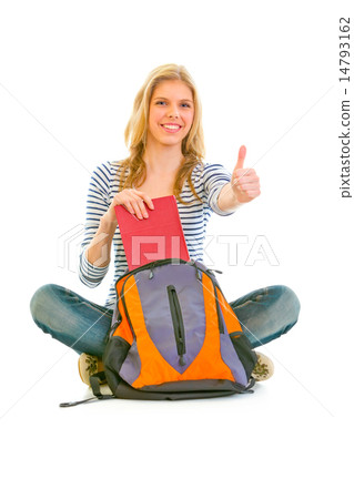 Sitting on floor smiling girl geting book from schoolbag and showing thumbs up gesture. 14793162