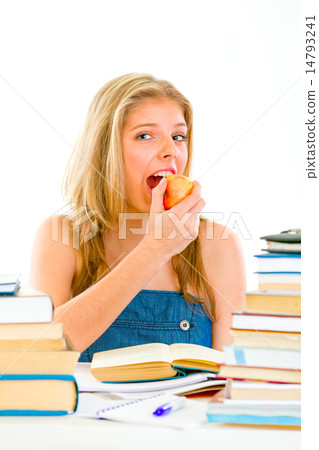 Smiling teengirl sitting at table with books and eating apple. 14793241